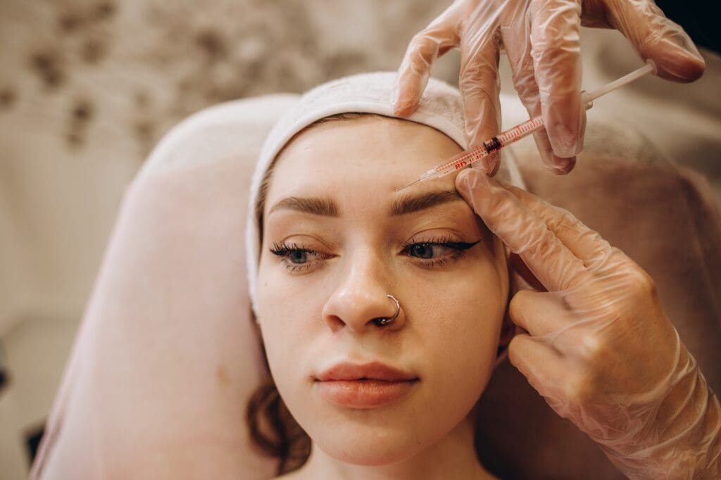 Portrait of young Caucasian woman getting botox cosmetic injection in forehead. Beautiful woman gets